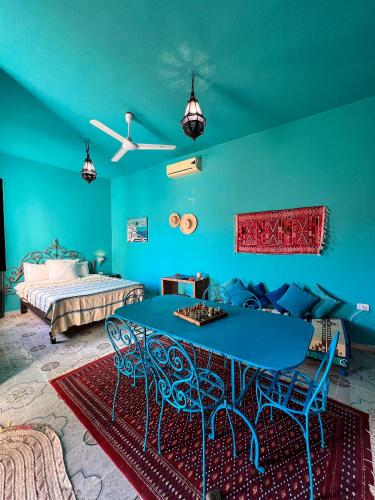 a blue room with a bed and a blue table and chairs at Dar Noor in Tozeur
