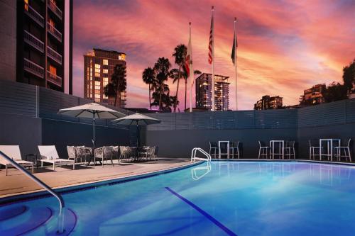 a swimming pool with a sunset in the background at The DEXTRO Little Italy, BW Premier Collection in San Diego