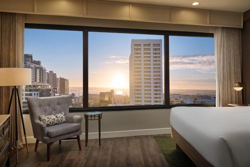 a hotel room with a bed and a chair and a large window at The DEXTRO Little Italy, BW Premier Collection in San Diego