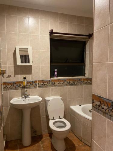 a bathroom with a toilet and a sink and a tub at Castle Ridgeview guesthouse in Pretoria