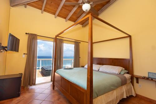 a bedroom with a canopy bed and a balcony at The Breeze in St Thomas