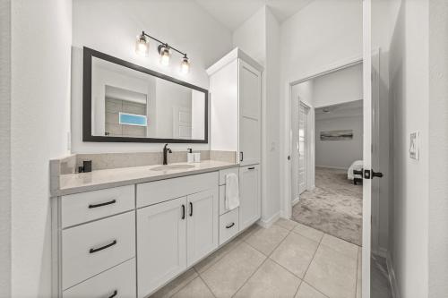 Un baño blanco con lavabo y espejo. en Spacious Haven in Shady Brook With Golfcart and King Bed, en Sumterville
