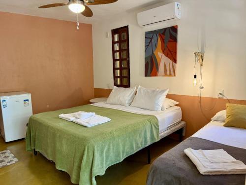 a bedroom with two beds with green sheets and a fan at Suítes Lamparina in Sao Jorge