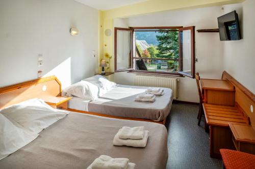 a hotel room with two beds and a window at Résidence des Touristes in Pierrefitte-Nestalas