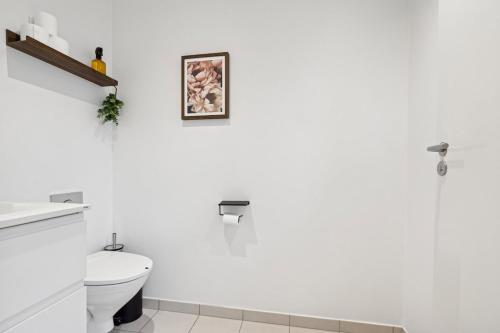 une salle de bain blanche avec des toilettes et un tableau au mur dans l'établissement Cozy Townhouse near Copenhagen, à Rødovre