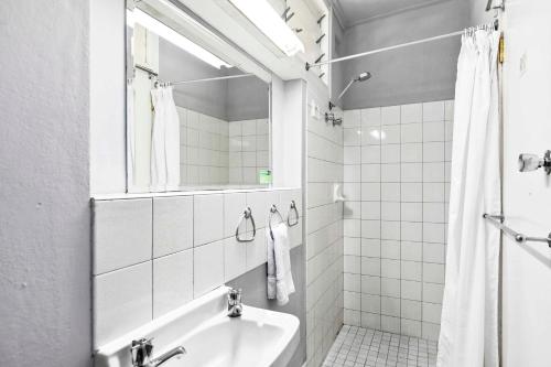 a white bathroom with a sink and a mirror at Arkana Motel in Maryborough