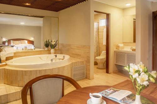 a large bathroom with a tub and a bedroom at Hotel Park Suites in Lima