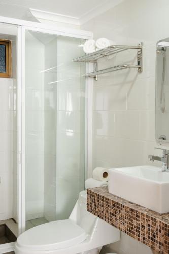 a white bathroom with a toilet and a sink at Mahia hotel Reñaca in Viña del Mar