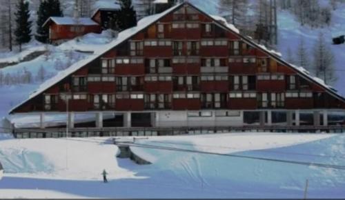 a large building in the snow with a rink in front at Bardoney Ski Lodge in Breuil-Cervinia
