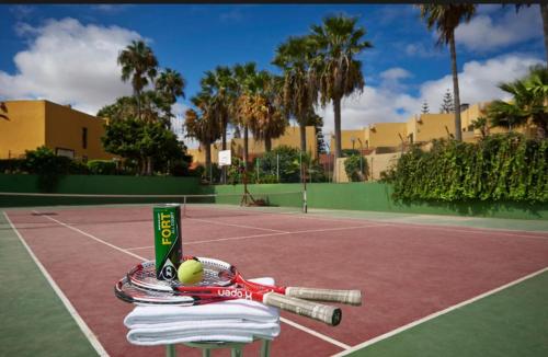 ein Tennisschläger und ein Ball auf einem Tennisplatz in der Unterkunft Atlantic Garden Andrew apartments Pool air conditioning in Corralejo