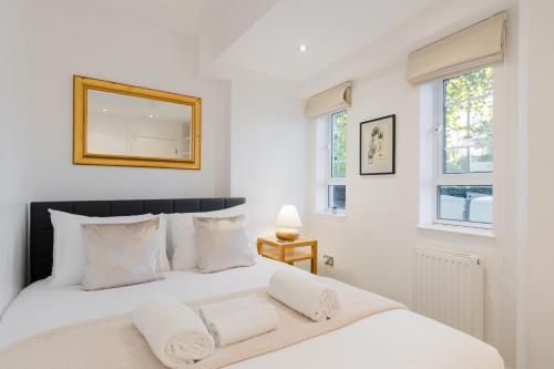a bedroom with a white bed with a mirror on the wall at Chelsea Luxe in London