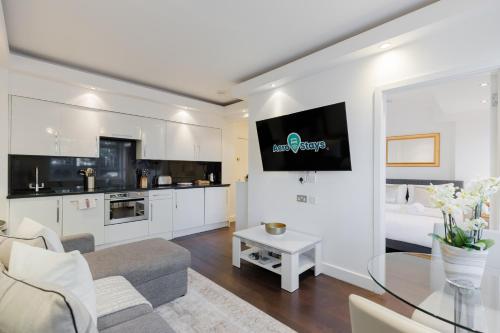 a living room with a couch and a tv on a wall at Chelsea Luxe in London