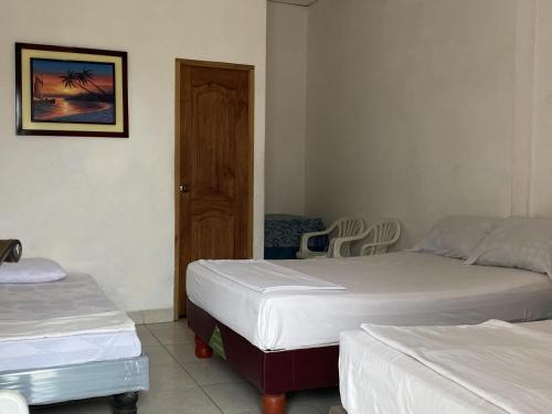 a bedroom with two beds and a door with a chair at Hostal La Cabaña Típica in Playas