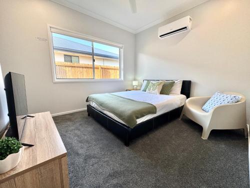 a bedroom with a bed and a window and a chair at Hillcrest Retreat - Cozy Studio with Private Entry in Boronia Heights