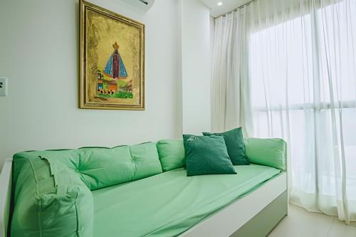 ein grünes Sofa in einem Zimmer mit einem Fenster in der Unterkunft Flat Praia de Maracaípe - Porto de Galinhas in Porto De Galinhas