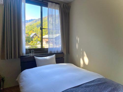 een bed in een kamer met een groot raam bij スパイシーシャレー in Hakuba