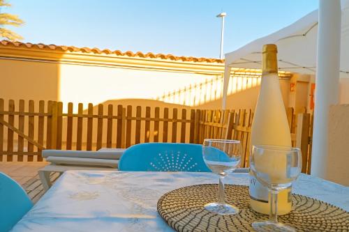 a bottle of wine sitting on a table with two glasses at Cozy Bungalow Maspalomas Green in Maspalomas