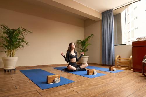 una mujer sentada en el suelo en una pose de yoga en Hotel Park Suites Lima, Barranco, en Lima