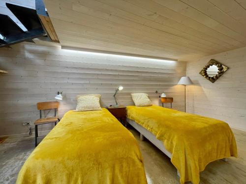 two beds in a room with yellow sheets at Maison cosy avec cour privative au cœur de l'Auvergne - FR-1-582-316 in Lempdes sur Allagnon