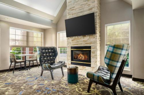 a living room with two chairs and a fireplace at Residence Inn by Marriott Portland Scarborough in Scarborough