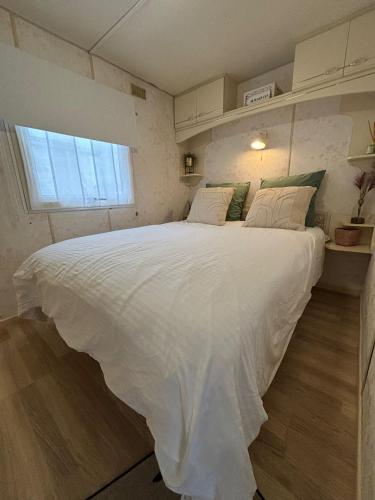 a large white bed in a room with a window at Tiny Beach Cottage - New Vennepark Wenduine in De Haan
