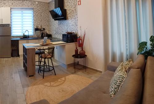 Una sala de estar con un sofá y una cocina. en HomeLand Place AL, en Horta