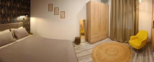Un dormitorio con una cama y una silla amarilla. en HomeLand Place AL, en Horta