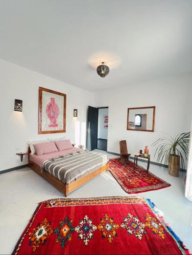a bedroom with a bed and two rugs at Villa Lala Argana in Essaouira