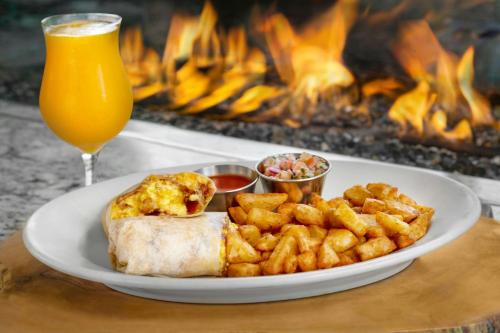 パロアルトにあるコートヤード パロ アルト ロス アルトスの一皿の食べ物とグラス一杯のオレンジジュースと火