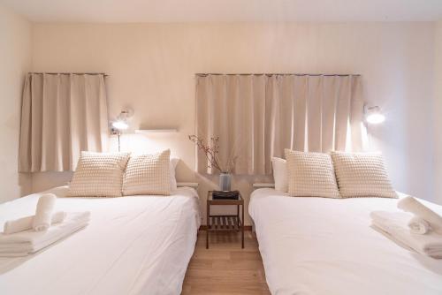two beds in a room with white sheets and pillows at Lido North Shinagawa in Tokyo