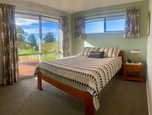 een slaapkamer met een bed en een groot raam bij Mapua - Rural bliss in Tasman