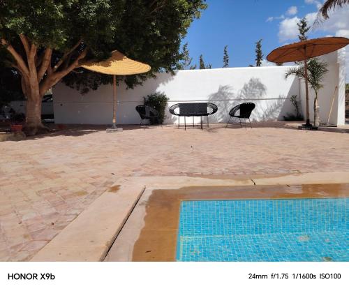 a swimming pool with two chairs and an umbrella at Ferme d'hôtes Aghbalou in Sefrou