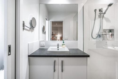 a white bathroom with a sink and a shower at Stylish Coastal Retreat in Ocean Grove