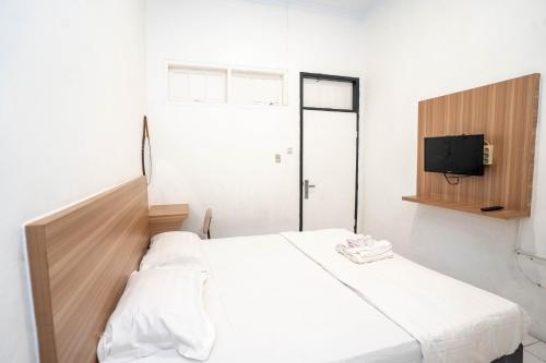 ジャカルタにあるTamastu House Pasar Baru Jakartaの白いベッドとテレビのある寝室