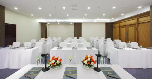 a conference room with white tables and flowers on them at Aristo Saigon Hotel in Ho Chi Minh City