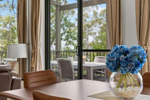 a vase filled with blue flowers sitting on a table at Villa Piccola Casa, Premier 2 Storey Villa, 2 Bedrooms, both with private ensuites, with third toilet on the ground floor in Pokolbin
