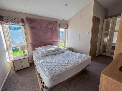 - une chambre avec un lit avec une tête de lit rose et 2 fenêtres dans l'établissement Beautiful Lodge With Decking In Hunstanton At Manor Park Ref 23195K, à Hunstanton