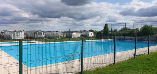 ein großer Pool hinter einem Zaun in der Unterkunft Tiny Beach Cottage - New Vennepark Wenduine in De Haan