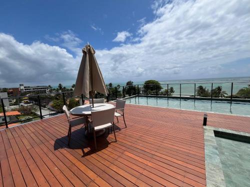 um pátio com uma mesa, um guarda-sol e uma piscina em Tamandaré Mar de Campas Flat 218 Carneiros em Tamandaré
