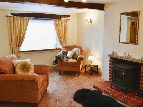a living room with a chair and a fireplace at Jug And Glass Cottage in Upper Langwith