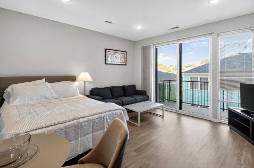 Un dormitorio con una cama y un sofá y un balcón. en Stylish Downtown Escape Near IU and Cafes, en Bloomington
