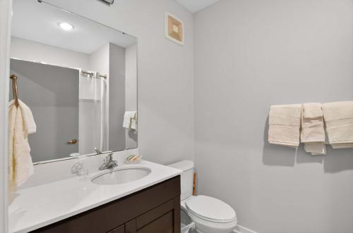 Un baño blanco con lavabo e inodoro. en Stylish Downtown Escape Near IU and Cafes, en Bloomington