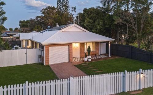 a small house with a white fence in a yard at 10 min walk to beach and cafés, Quiet area, Bikes in Byron Bay