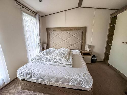 une chambre avec un lit avec des draps blancs et une fenêtre dans l'établissement Wonderful 6 Berth Caravan For Hire At Manor Park, Hunstanton, Norfolk Ref 23028S, à Hunstanton