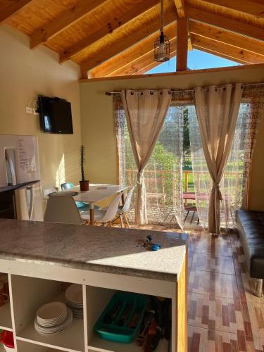 a kitchen and living room with a table and a couch at Cabañitas Zelada en un ambiente natural con piscina fogón Quincho Terraza parking full equipadas en 5000 mtrs in Algarrobo