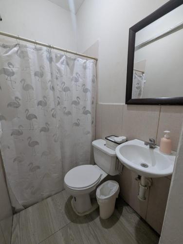 a bathroom with a toilet and a sink and a shower curtain at Villa San Valentin in San Pedro Sula