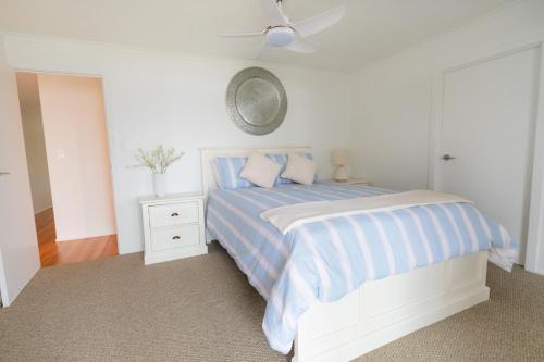 a white bedroom with a bed and a ceiling fan at River Shack Ballina 