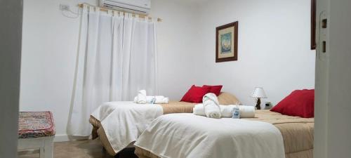 1 Schlafzimmer mit 2 Betten mit weißen und roten Kissen in der Unterkunft CasaMar in General Villegas