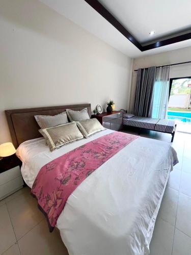 a bedroom with a large bed with a pink blanket at Dusit Garden Large Pool Villa in Na Jomtien