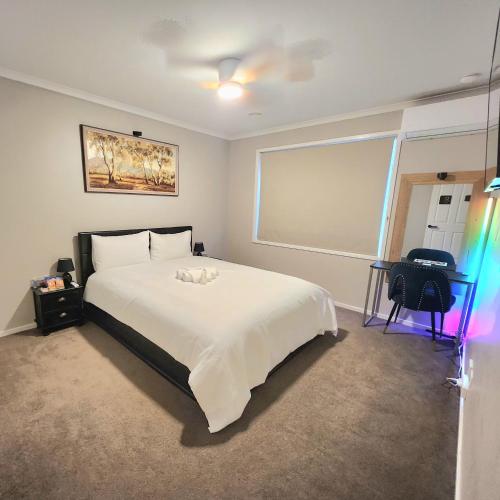 a bedroom with a large white bed and a desk at Private Room 1- The Minimalist Escape in Craigieburn